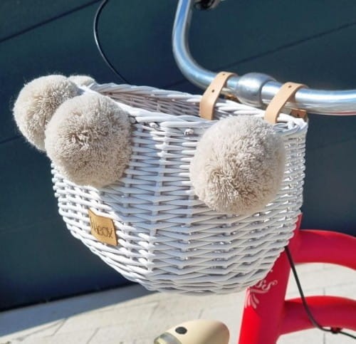 biały wiklinowy koszyk na rower dla dzieci Dumpy w paski z pomponami