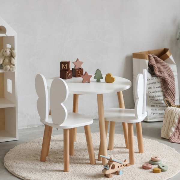 drewniany stolik dziecięcy z krzesełkami motylkami w stylu skandynawskim w jasnym pokoju dziecka